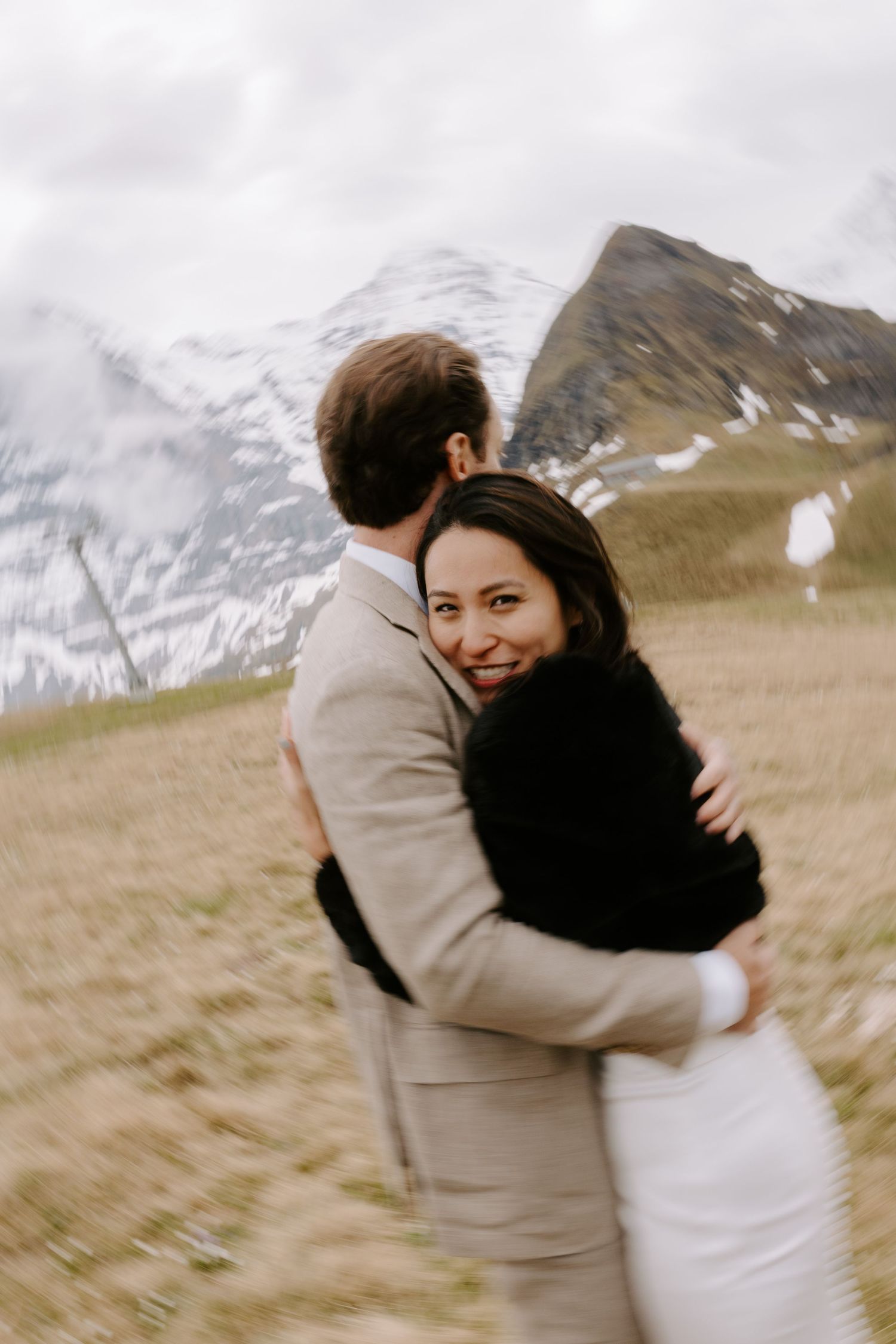 A couple shares an intimate moment on a mountainside during their wedding photoshoot.