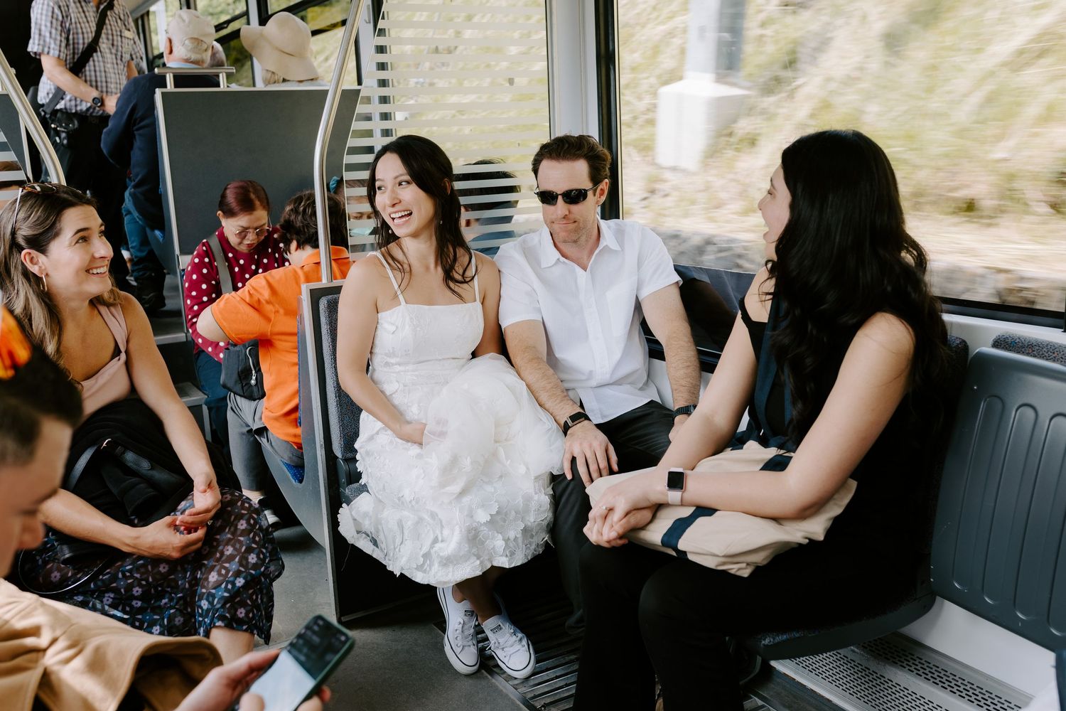 Wedding party guests chatting and relaxing inside a passenger vehicle during transportation.