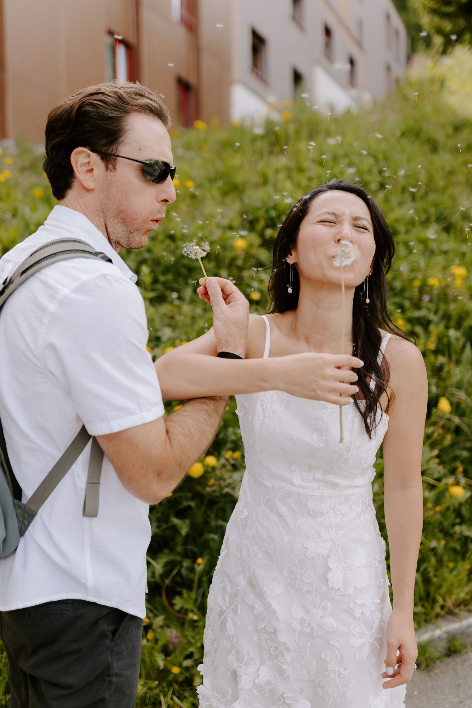 A playful couple blowing bubbles in formal attire during a summer wedding photo session.