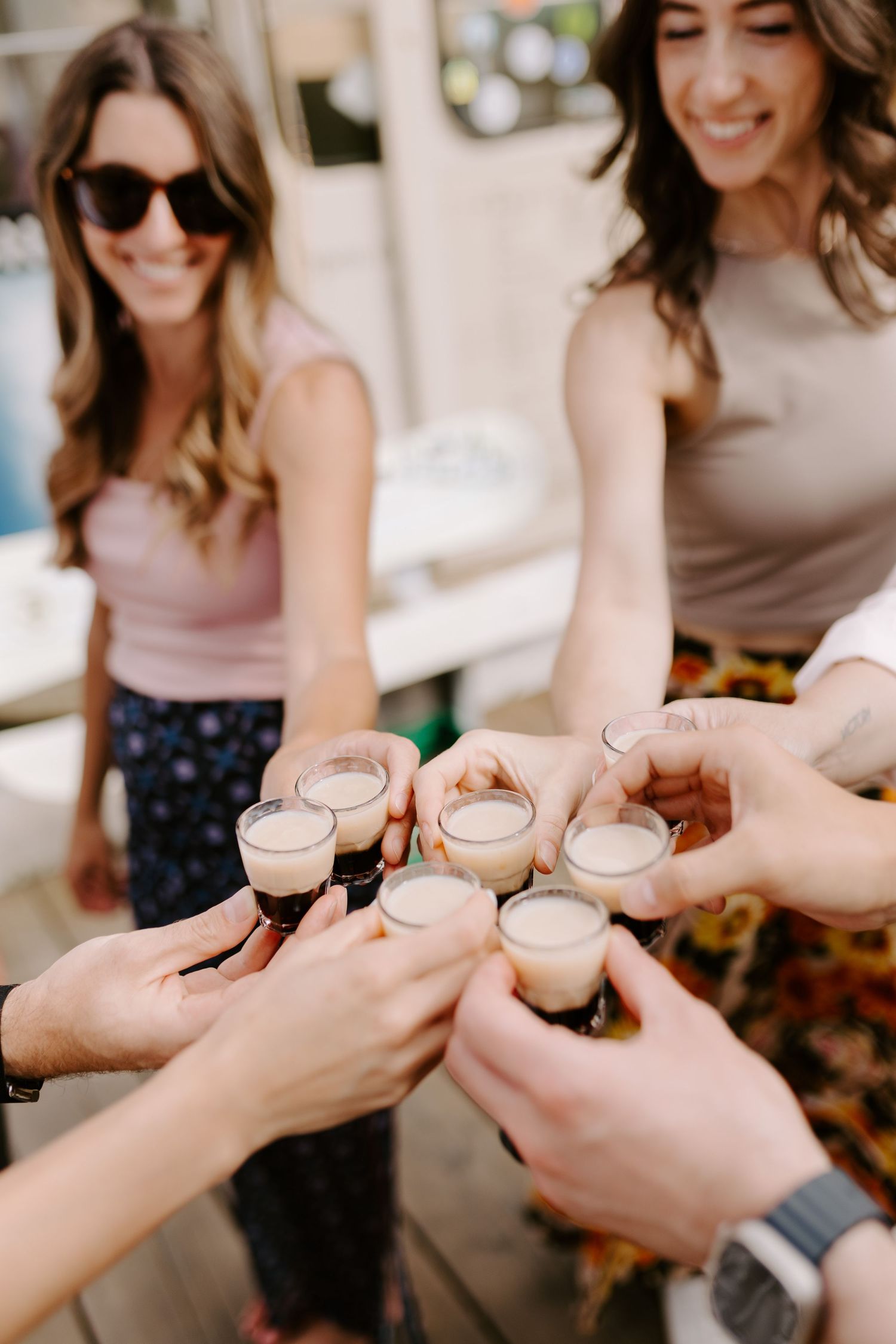 Friends toasting with cappuccinos in a casual gathering, hands reaching together in celebration.