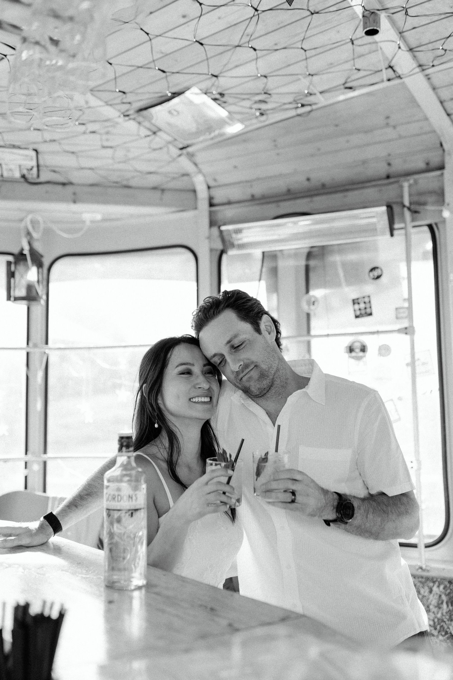 A romantic black and white photo shows a couple sharing an intimate moment in a vintage train car.