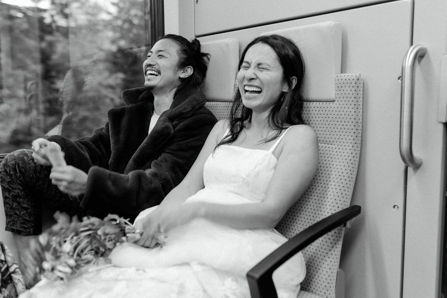 Candid black and white photo capturing laughter and joy during a train journey.
