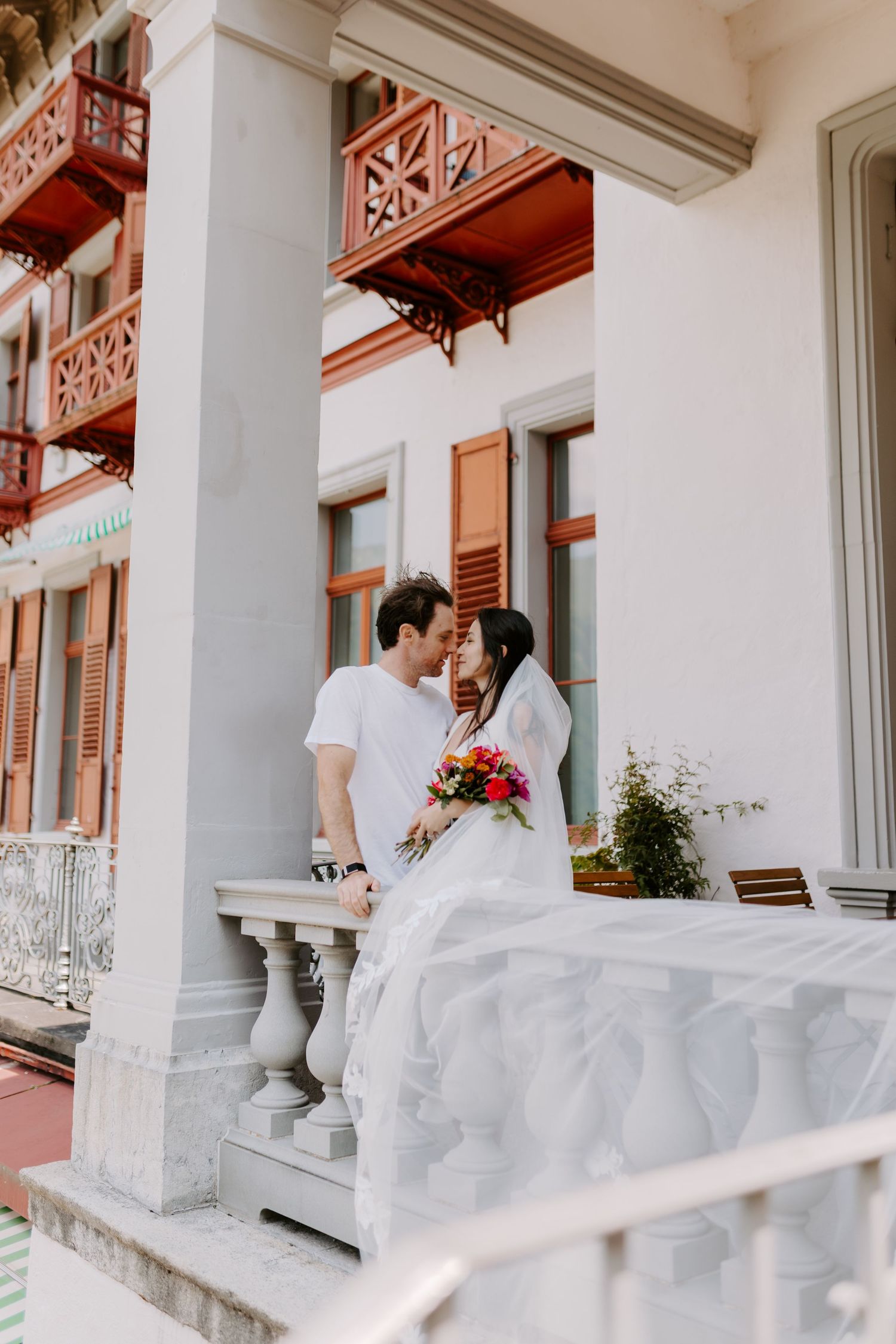 A romantic scene on a white balcony with ornate architectural details and colorful flowers.