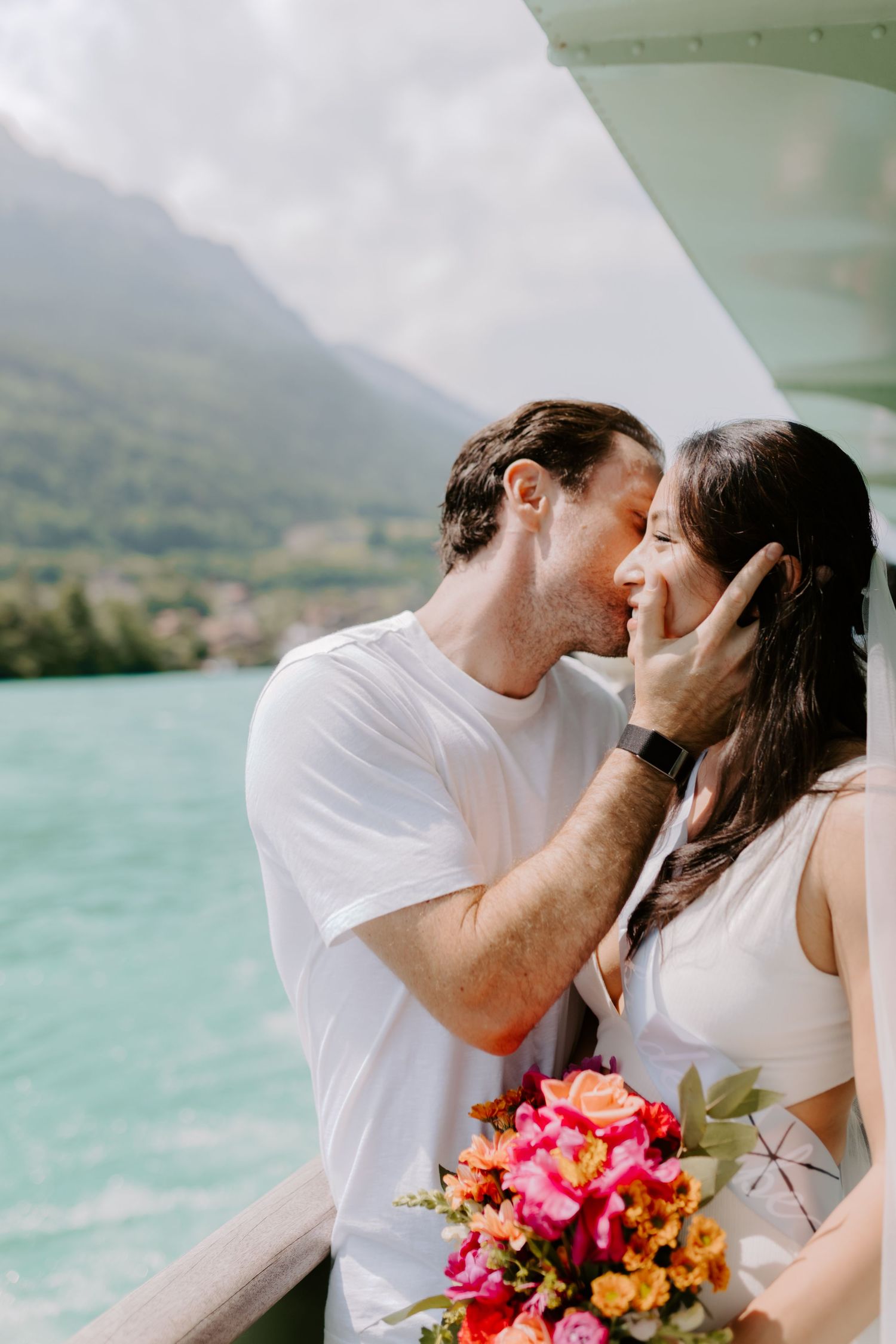A romantic moment shared with vibrant flowers against turquoise waters and mountain backdrop.