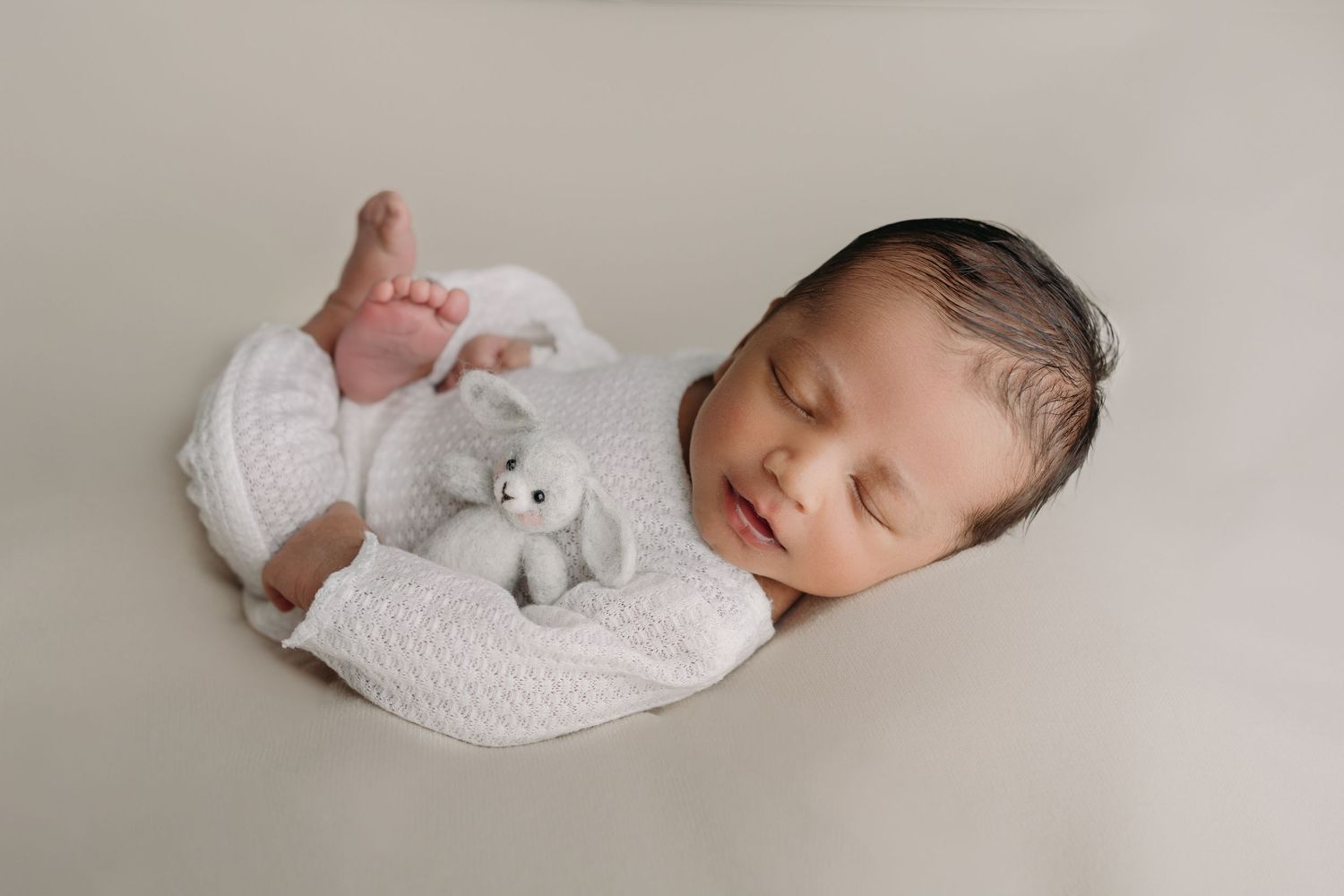 Posed newborn photo in studio with soft, neutral colors by Tampa newborn photographer