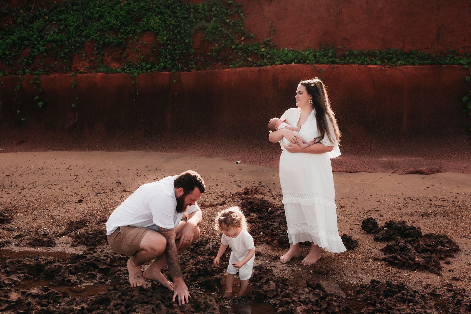 beautiful family session on the beach with red cliffs in the background and all wearing white