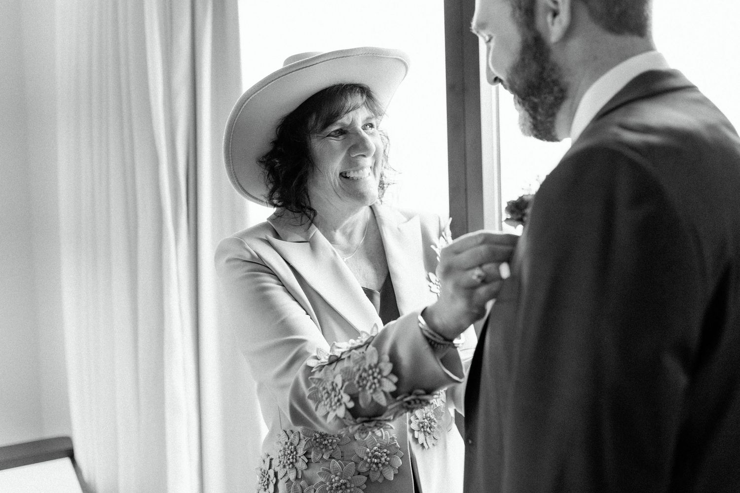 A candid black and white moment showing a mother sharing an emotional embrace with the groom.