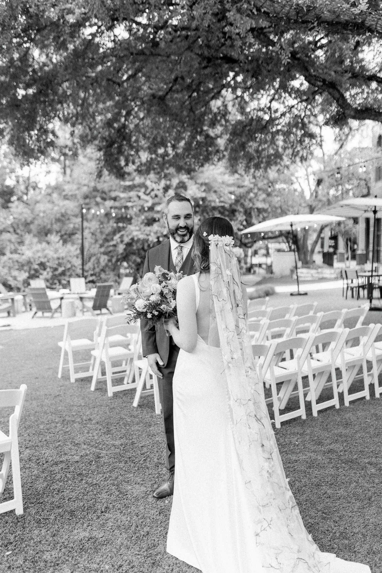 A wedding couple sharing a romantic moment on their wedding day among white garden chairs.