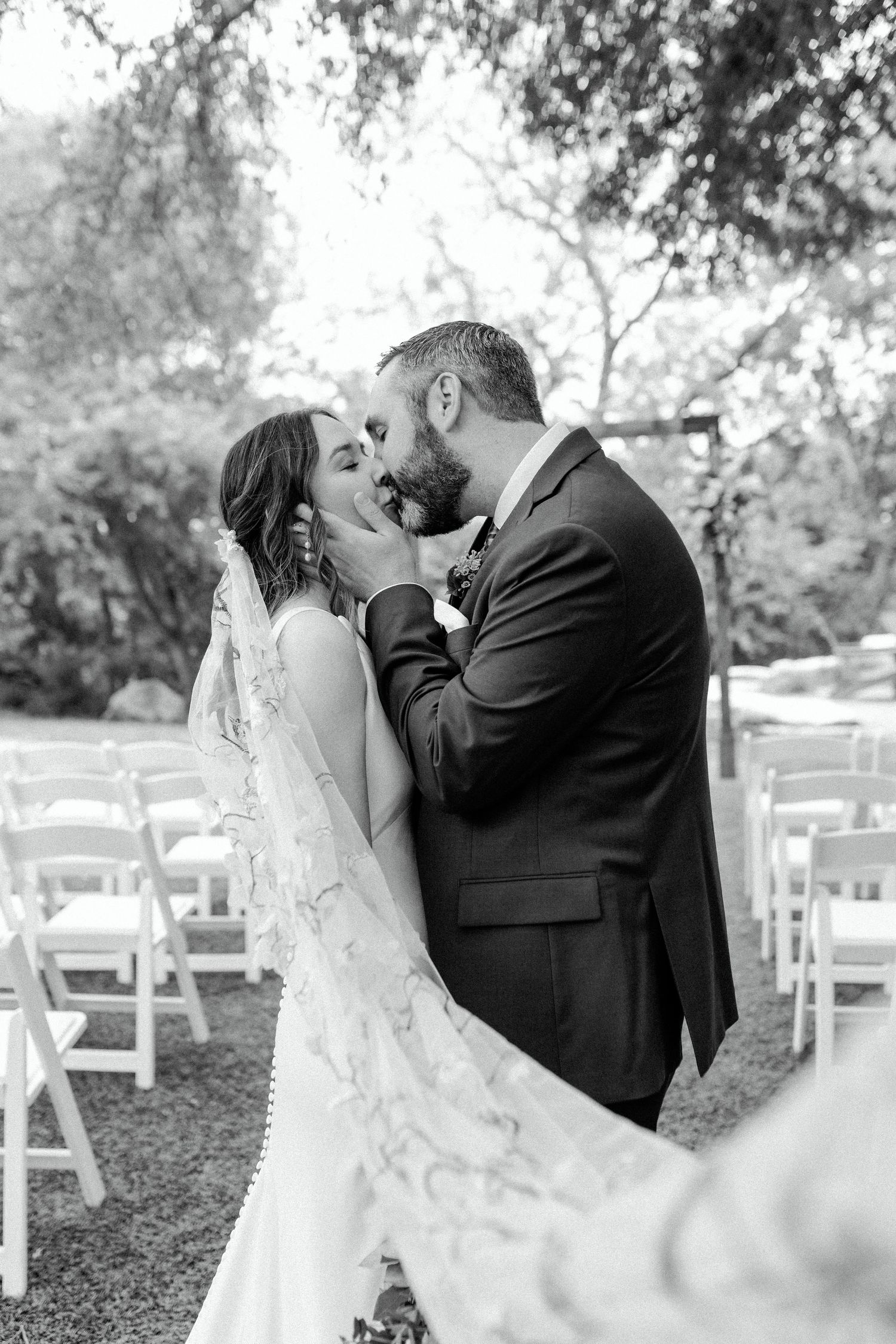 Romantic black and white wedding portrait in an outdoor garden setting.