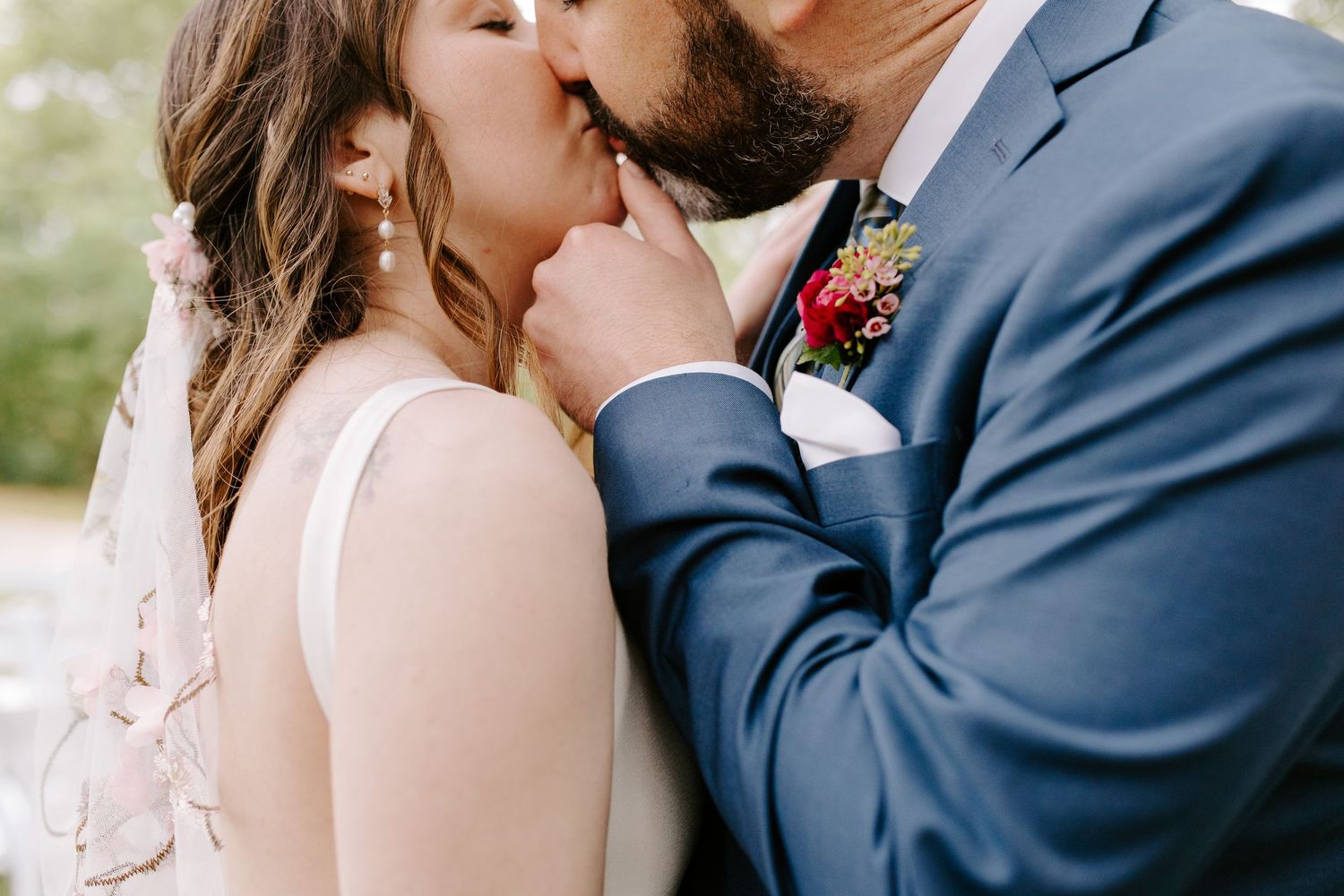 Close-up of two people sharing an intimate kiss at their outdoor wedding celebration.