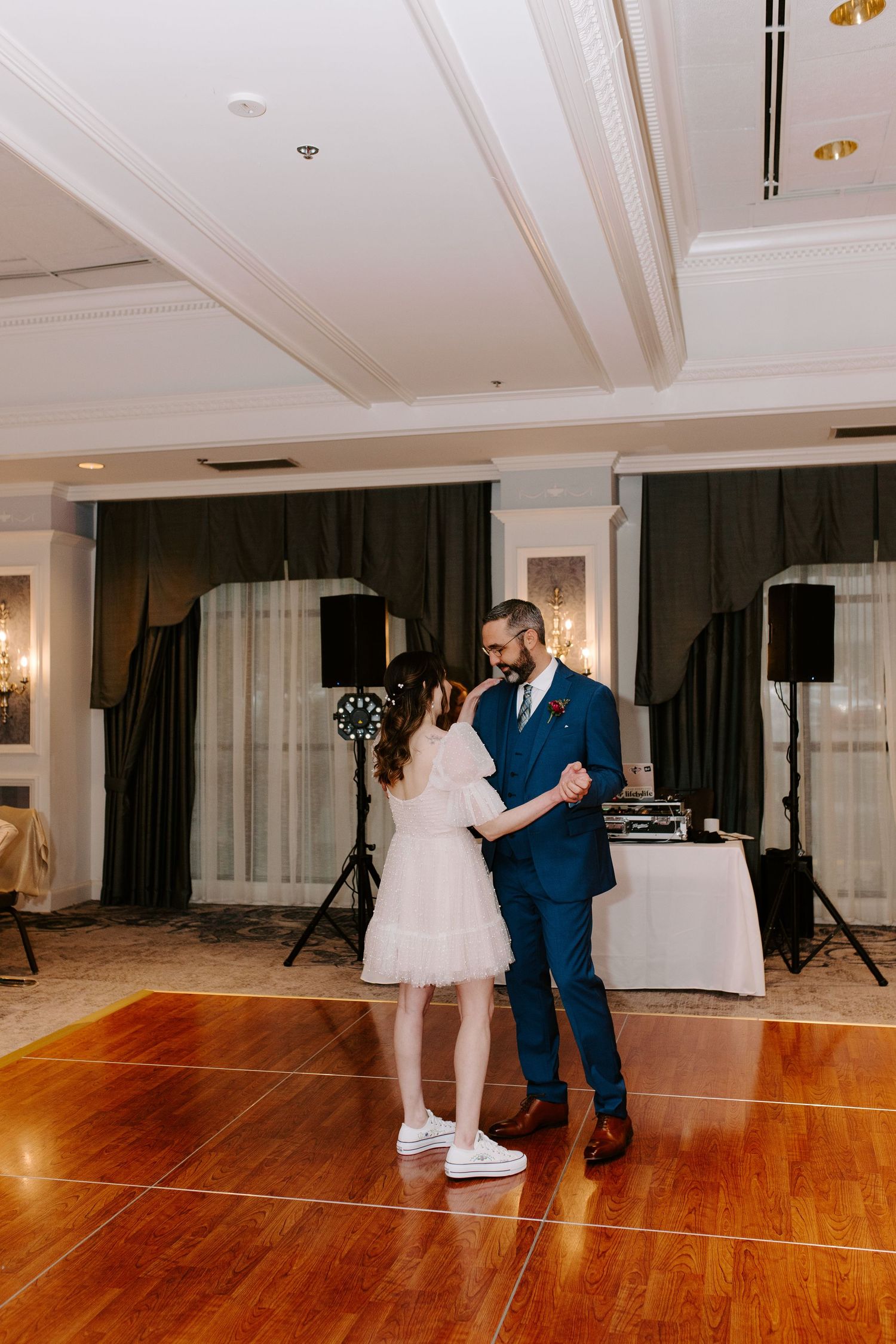 Reception dance floor lit by chandeliers with a dance couple enjoying a special moment.