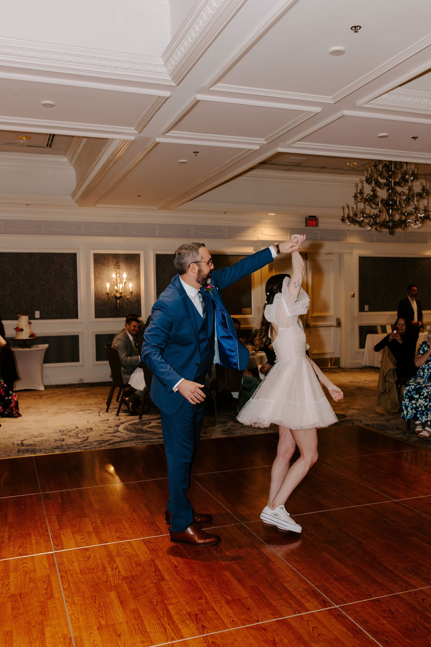 Wedding celebration with dancing couple on a polished hardwood floor in an elegant ballroom.