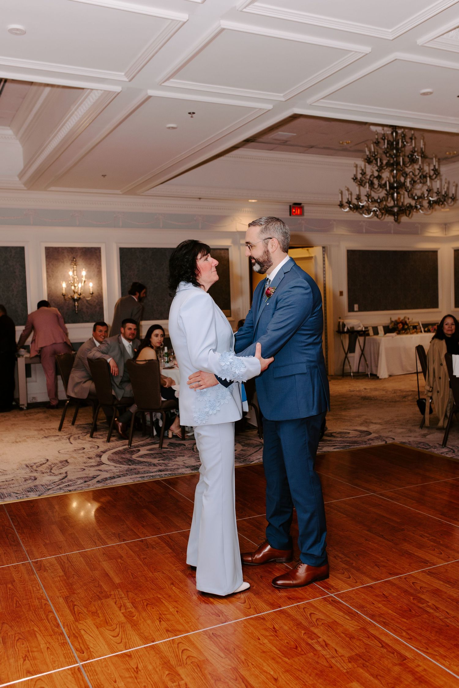 Couple sharing an intimate dance moment on a wooden floor at an elegant reception venue.