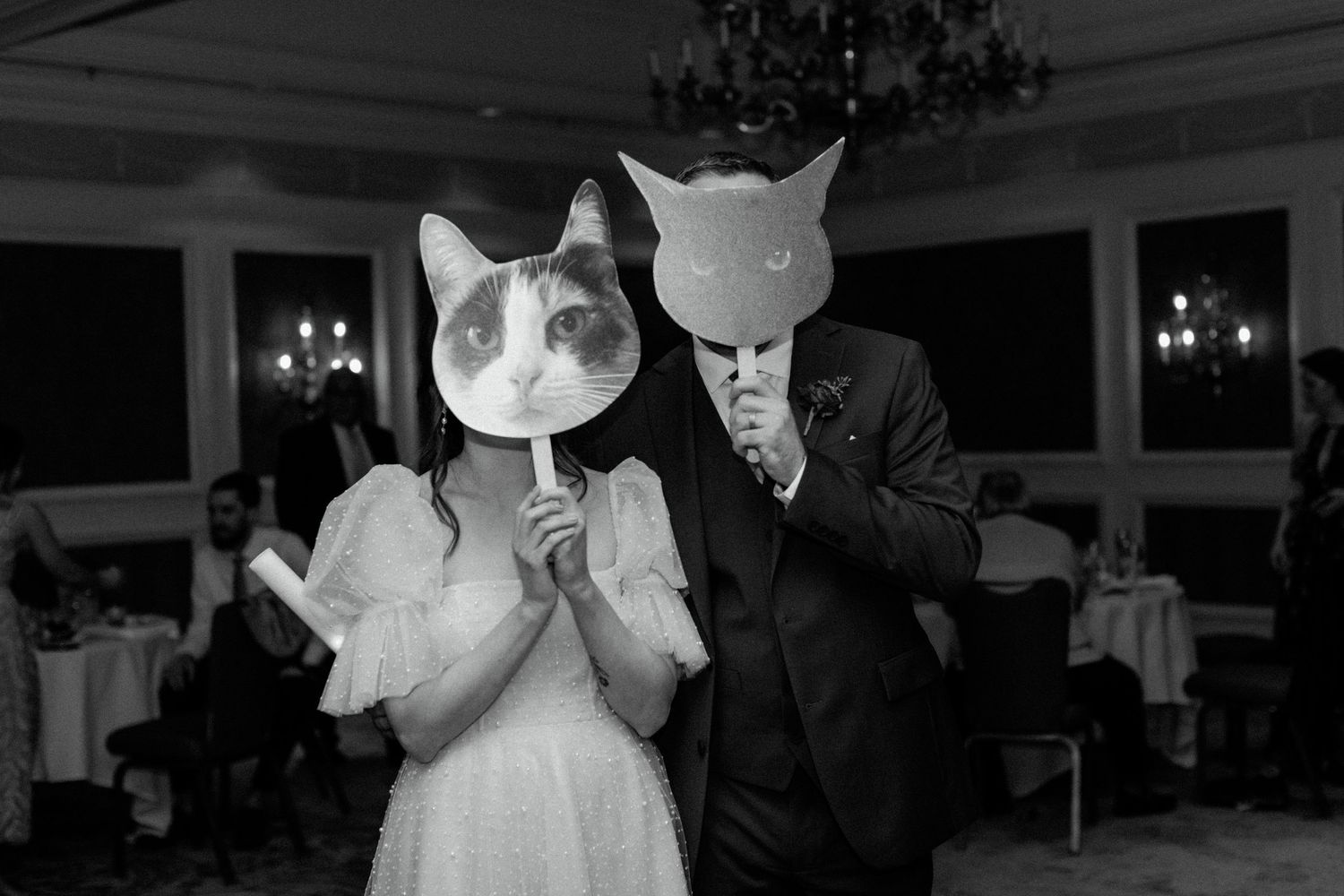 Couple wearing playful cat masks dance together at their wedding reception.