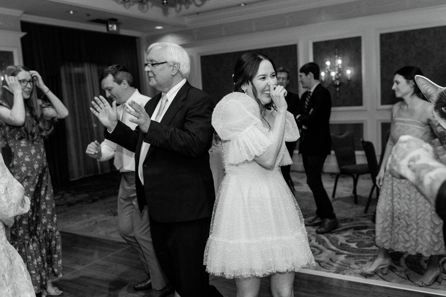 People dancing and enjoying themselves at a wedding reception in an elegant ballroom with chandeliers.
