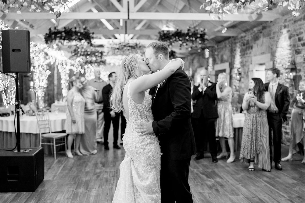 Wedding guests dance and celebrate on a brightly lit dance floor at an elegant indoor reception venue.