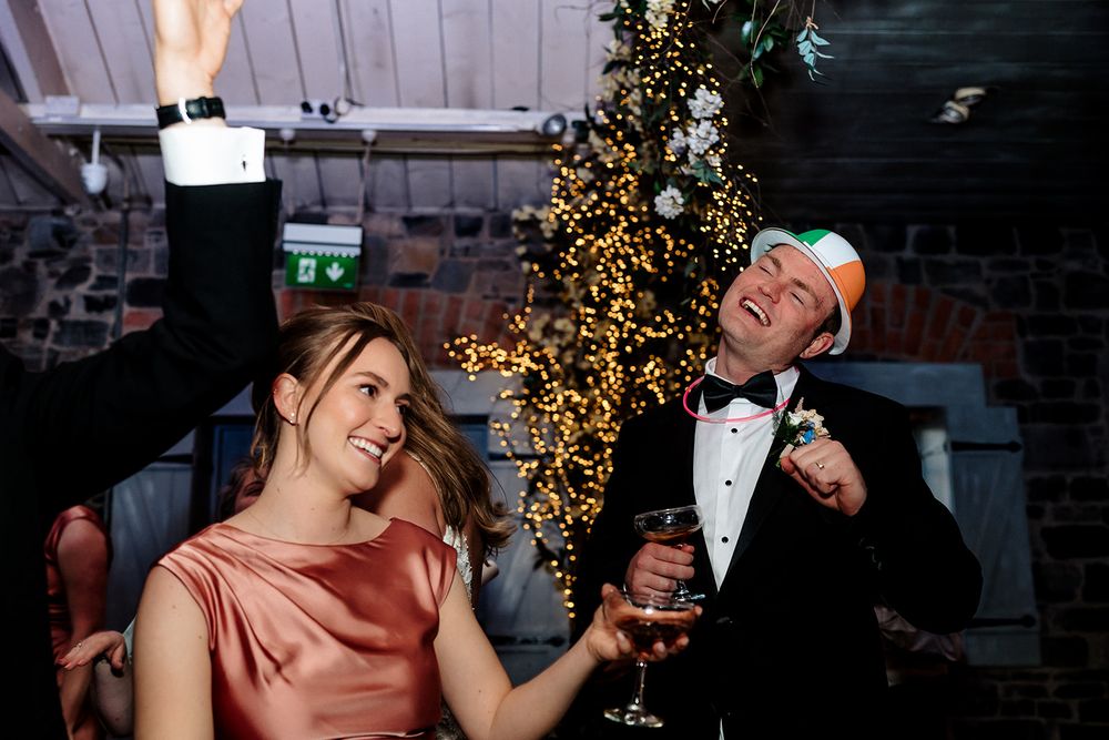 Two people dancing and celebrating at a festive party with a glowing Christmas tree in the background.