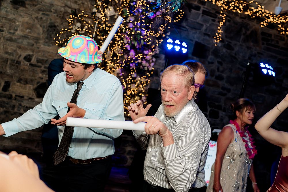 A group of people dancing and celebrating at a party with colorful lights in the background.