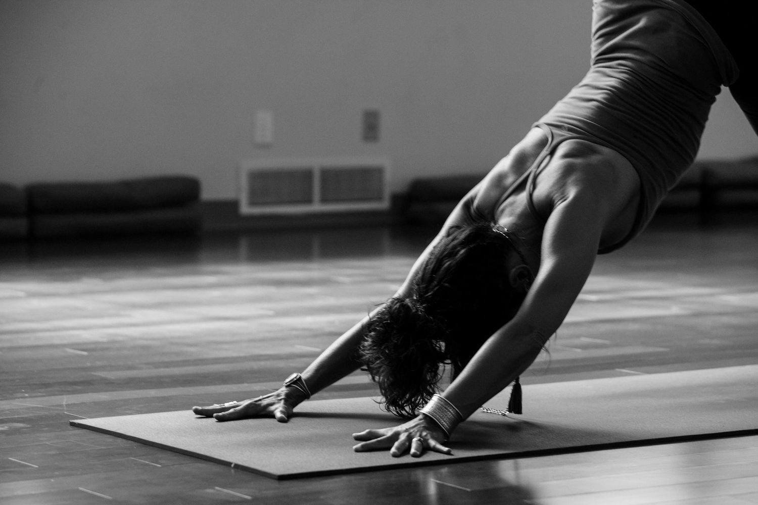 Black and white image of person doing downward dog yoga pose on mat.
