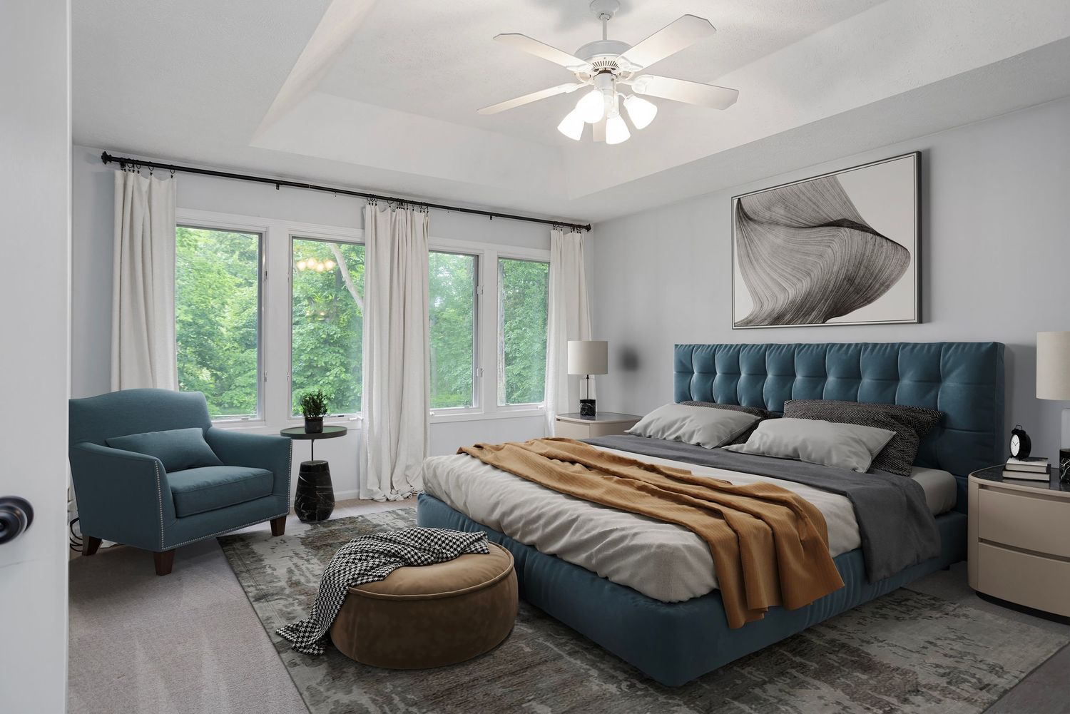 Virtually staged modern bedroom with king bed, blue upholstered headboard, large windows, cozy seating, and serene natural views.