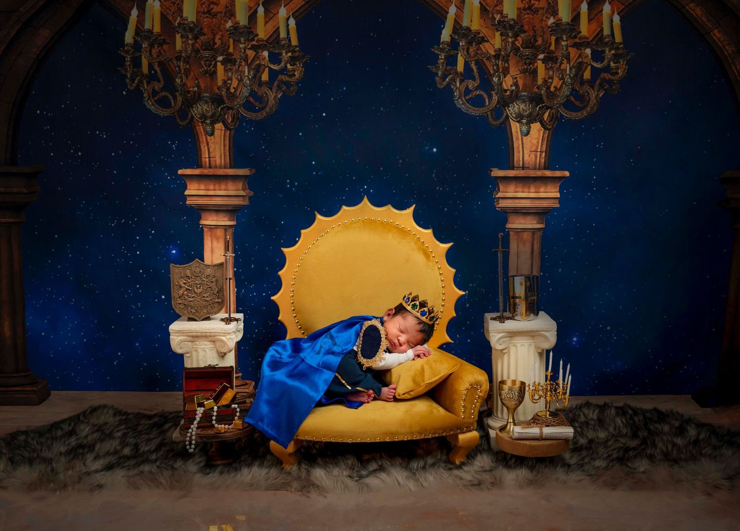 Dreamy newborn photo with moon-shaped prop and elegant chandeliers in a midnight blue setting.