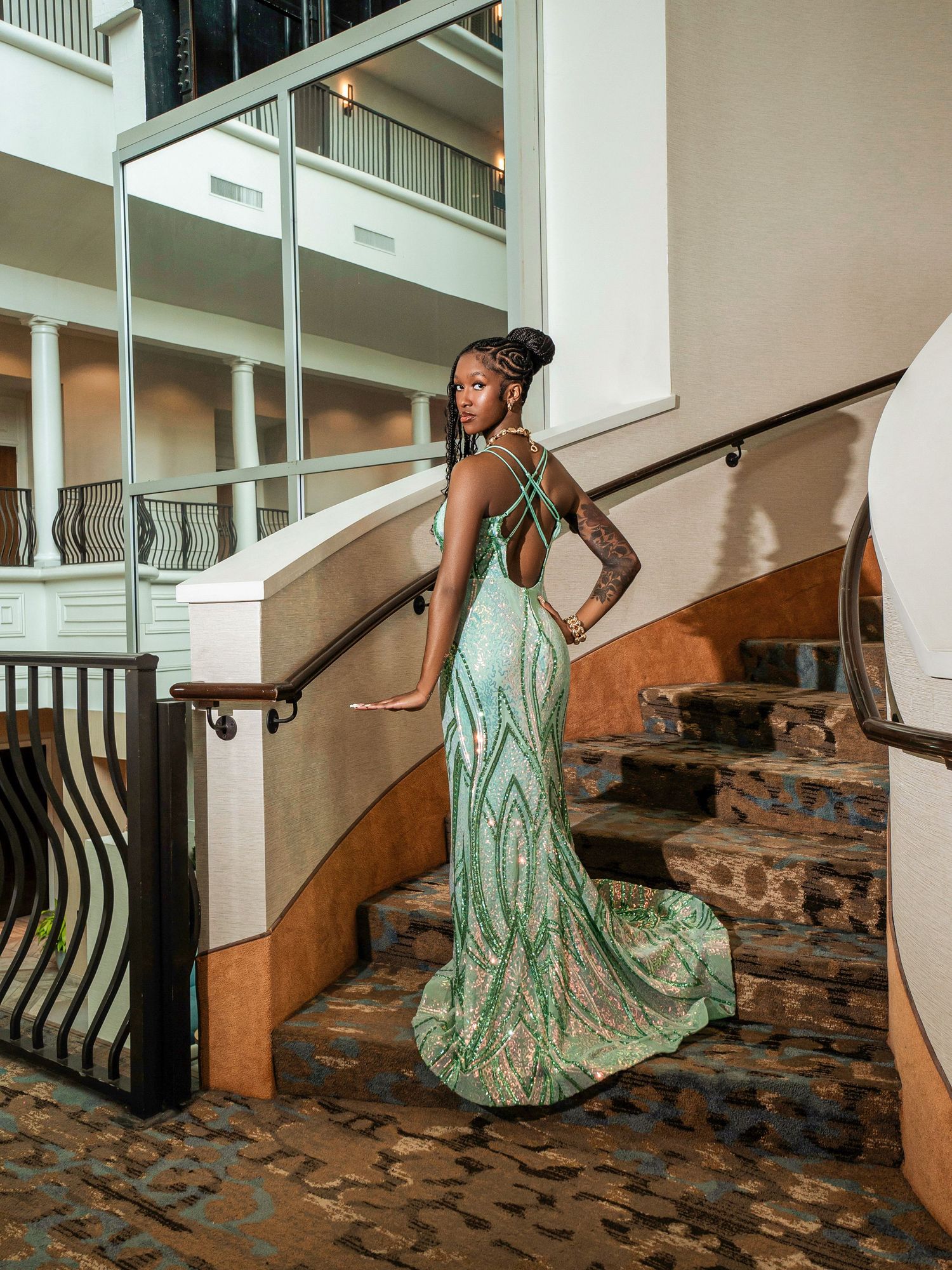 A stunning mint green sequined evening gown with a dramatic train showcased on an elegant stone staircase.