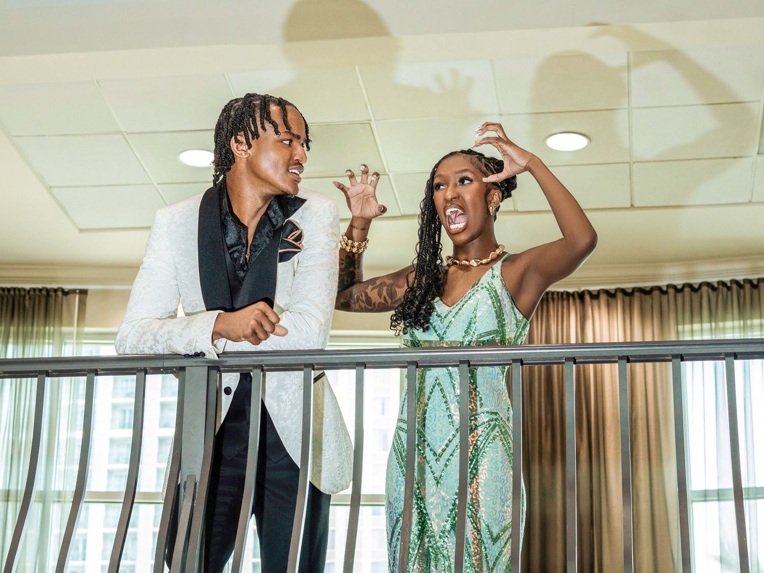 Two people in a banquet hall express joy and excitement while dancing in formal attire.