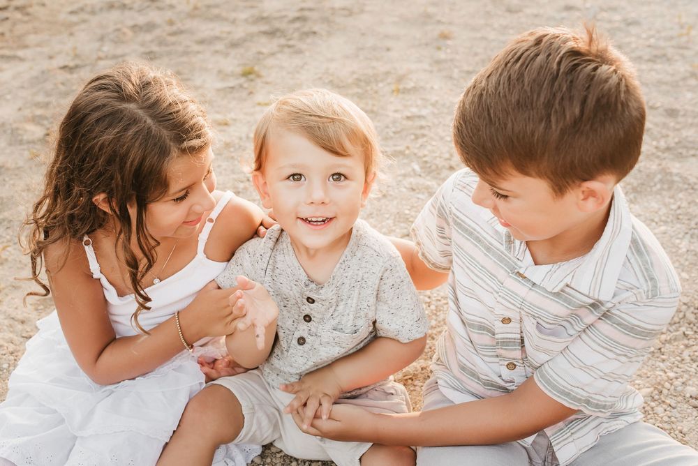 siblings play together on beach during family photos in cincinnati, ohio