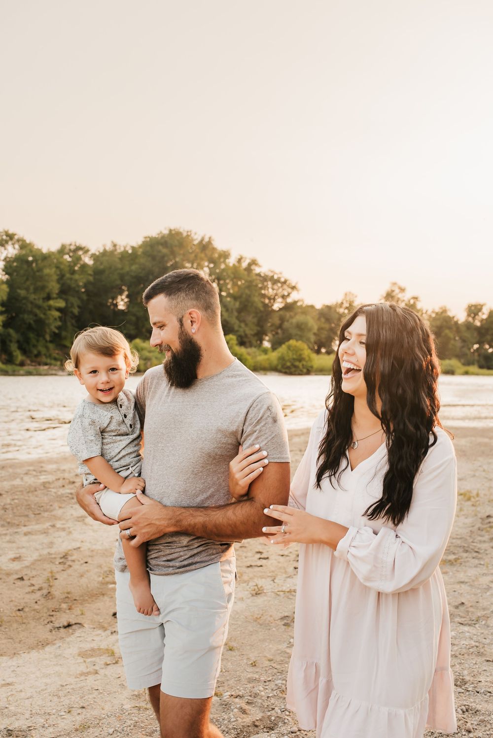 mom holds dad's arm as she laughs at her children playing near the water in ohio