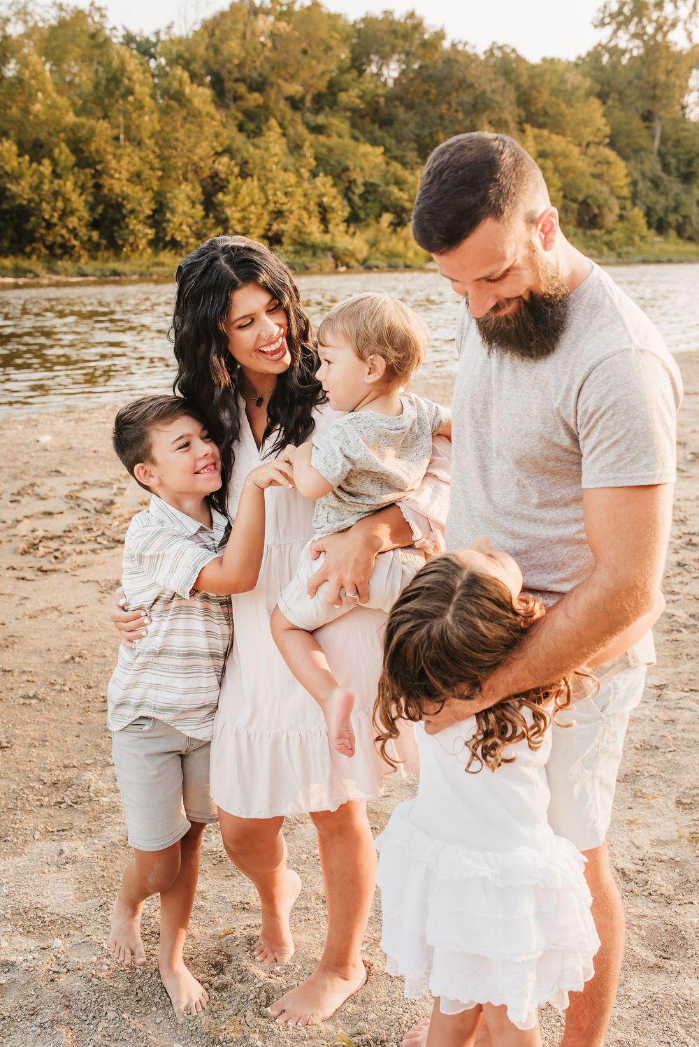 family laughs together on beach on little Miami river in ohio
