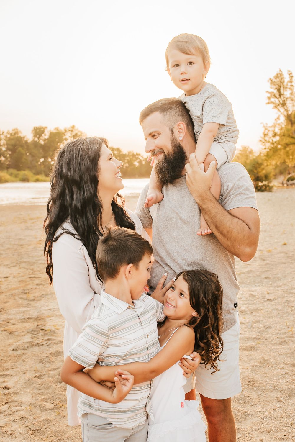 family enjoys the sunset together on rocky beach near cincinnati, ohio