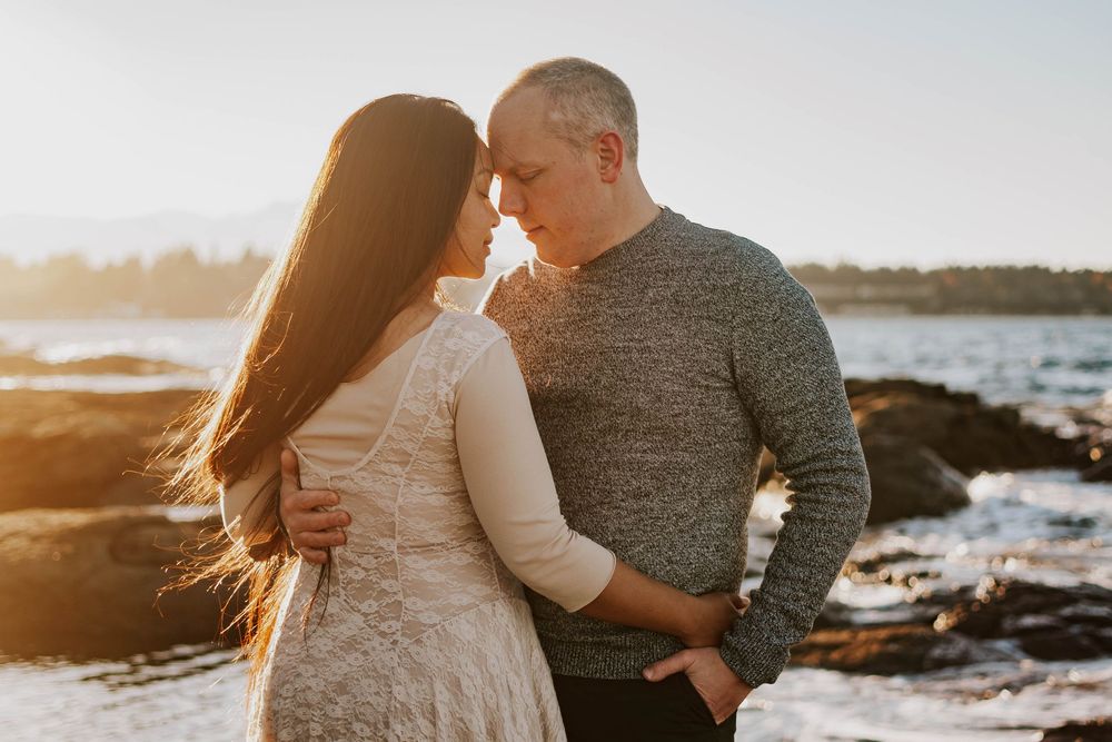Beautiful image taken at Madrona Point Parksville Vancouver Island of couple with foreheads together on beach shore during sunset photoshoot