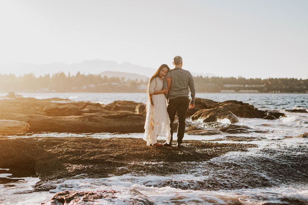 Beautiful image taken at Madrona Point Parksville Vancouver Island of couple hugging on beach shore during golden hour photoshoot