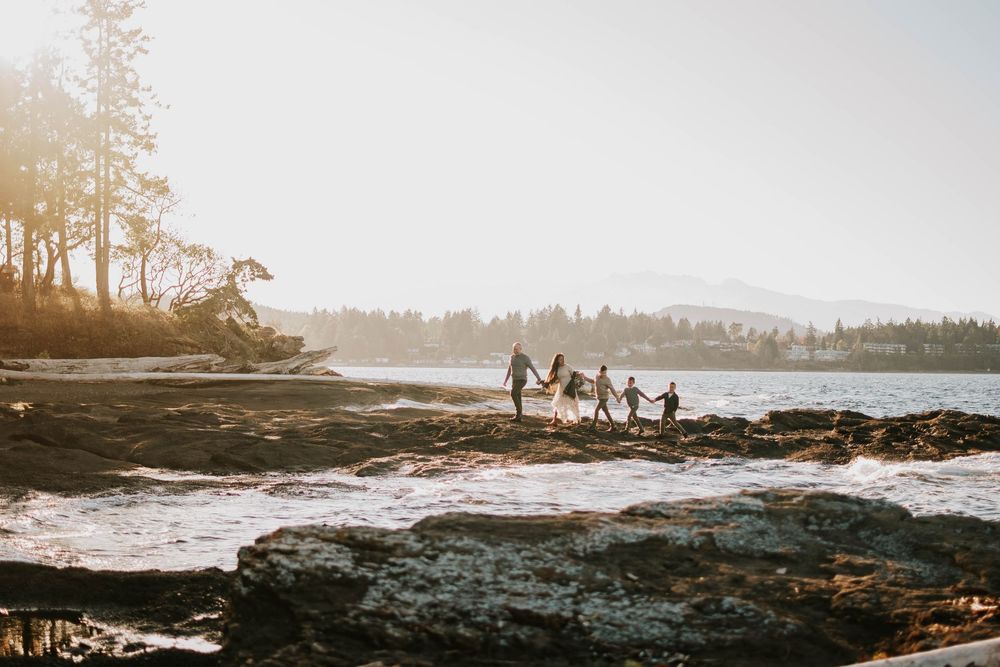 Parksville photography portrait of family walking along Madrona Point Beach on rocky shore on Vancouver Island during sunset photoshoot