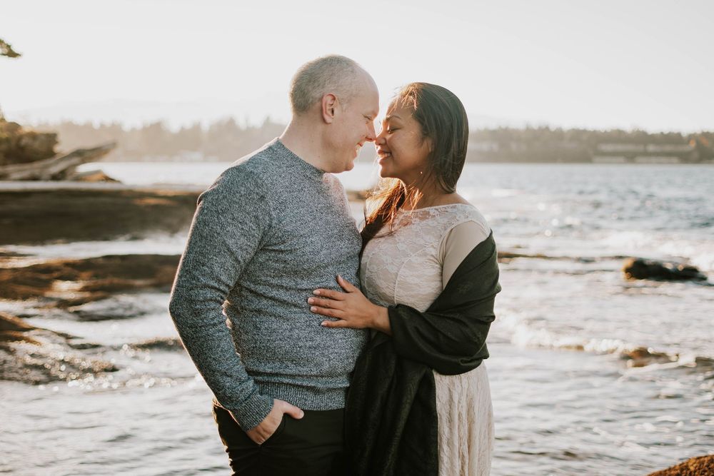 Parksville photography portrait of couple embracing along Madrona Point Beach on rocky shore on Vancouver Island sunset photoshoot
