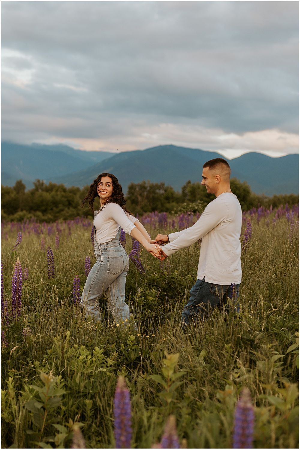 A couple taking NH engagement photos in a lupine field