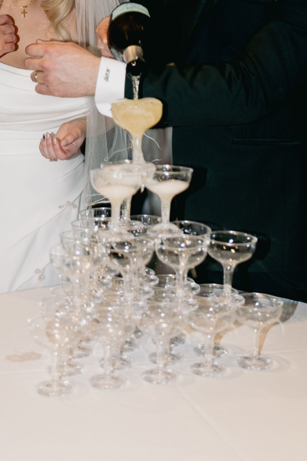 Champagne being poured into a tower of elegant crystal coupe glasses at an upscale event.
