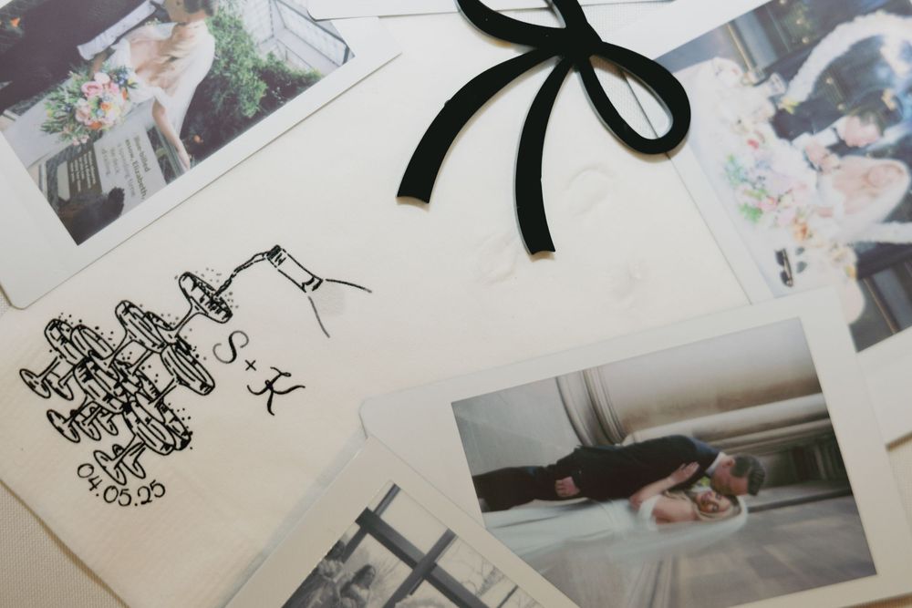 A collection of photographs spread out with a black ribbon bow and handwritten text visible in the corner.