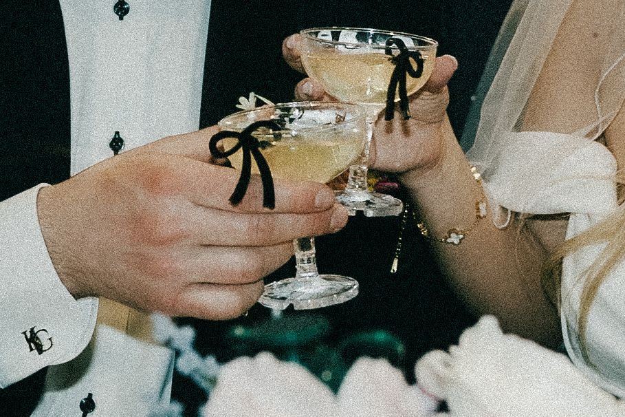 Three hands raise crystal champagne glasses for a celebratory toast in a dimly lit setting.