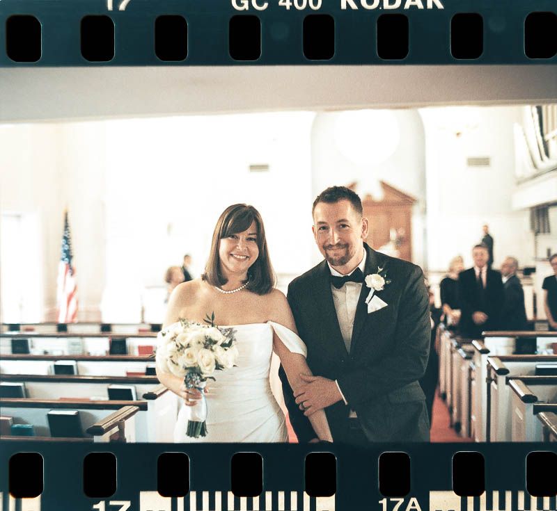 A happy couple walks down the church aisle together after their wedding ceremony. Christ First Church in Fox Chapel Pittsburgh PA 35mm Film.