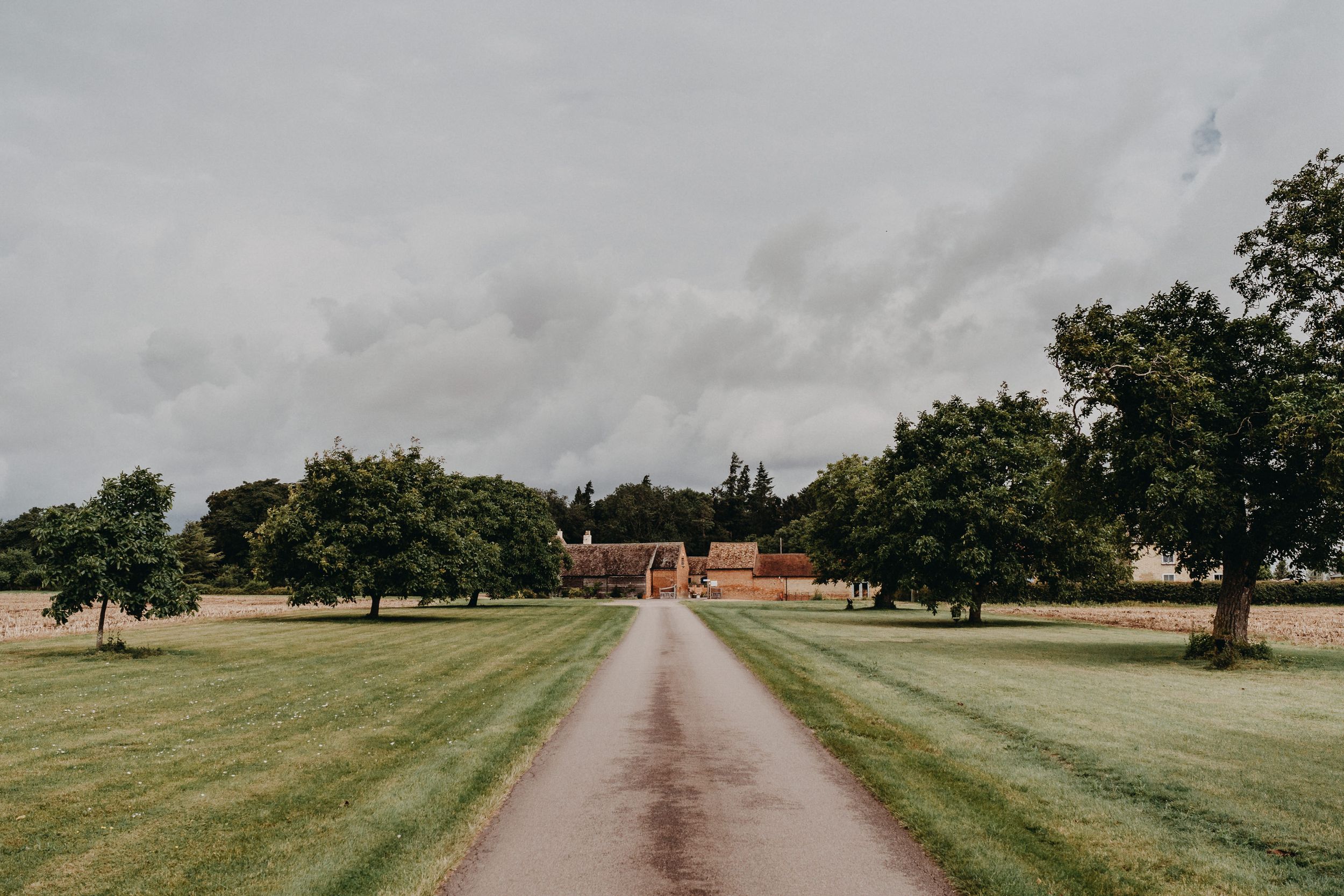 Long driveway leading to Bassmead Manor Barns through green fields and trees.