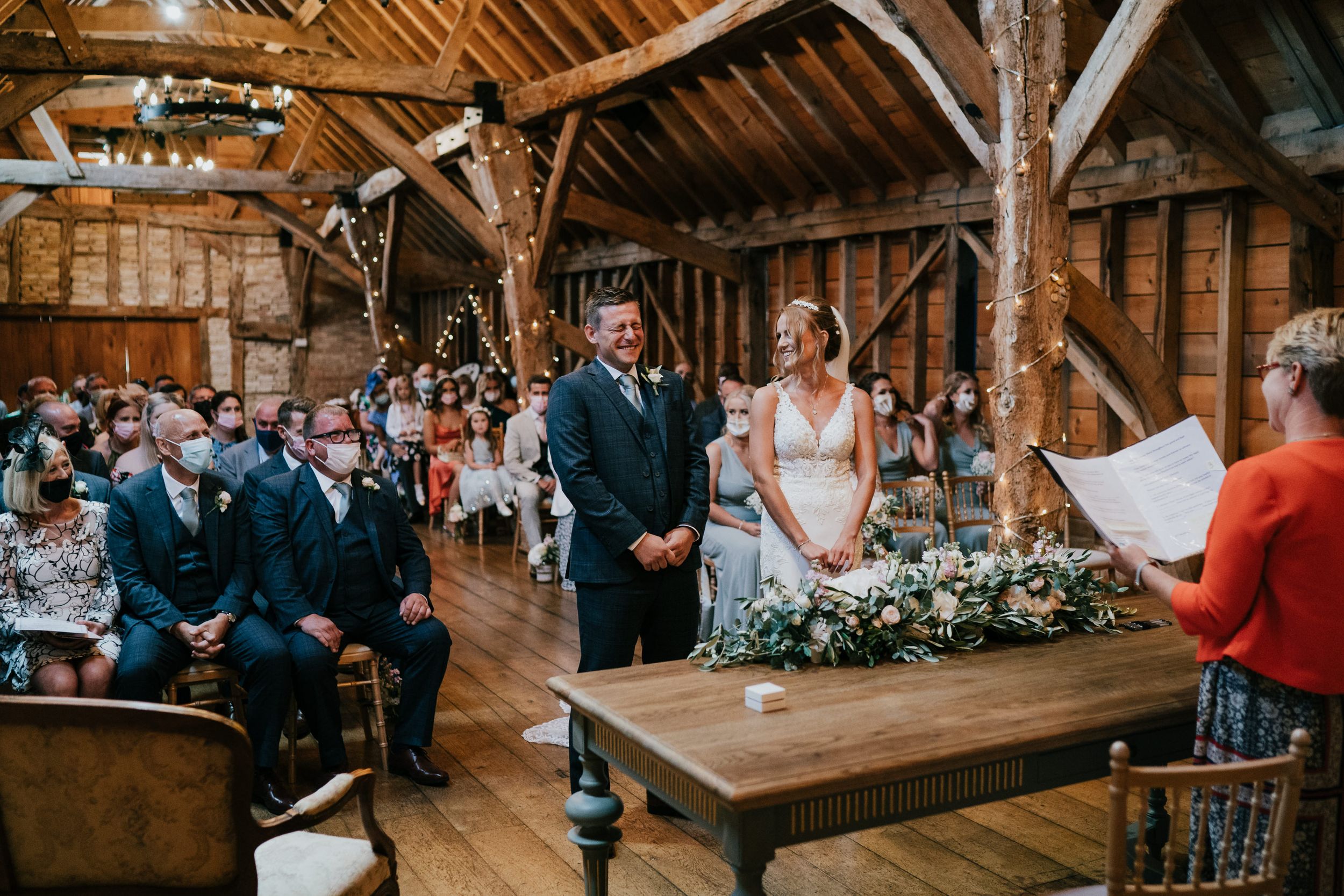Wedding ceremony in progress inside Rickety rustic barn with wooden beams and natural light.