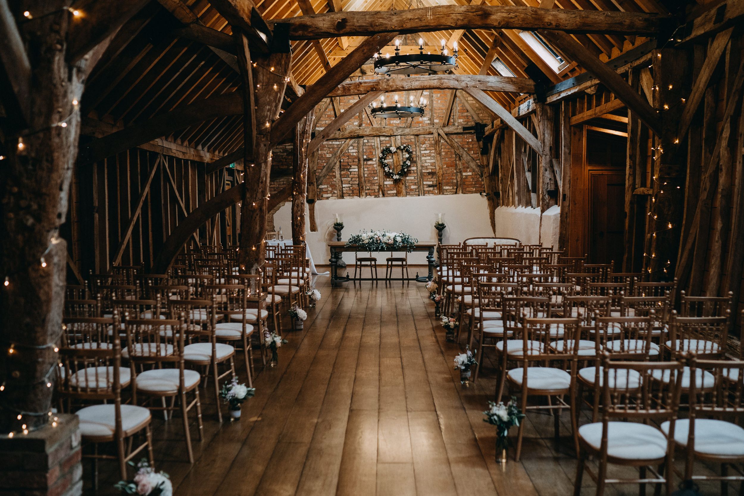 Rustic barn Bassmead Manor Barns with wooden beams and rows of chairs set up for ceremony.