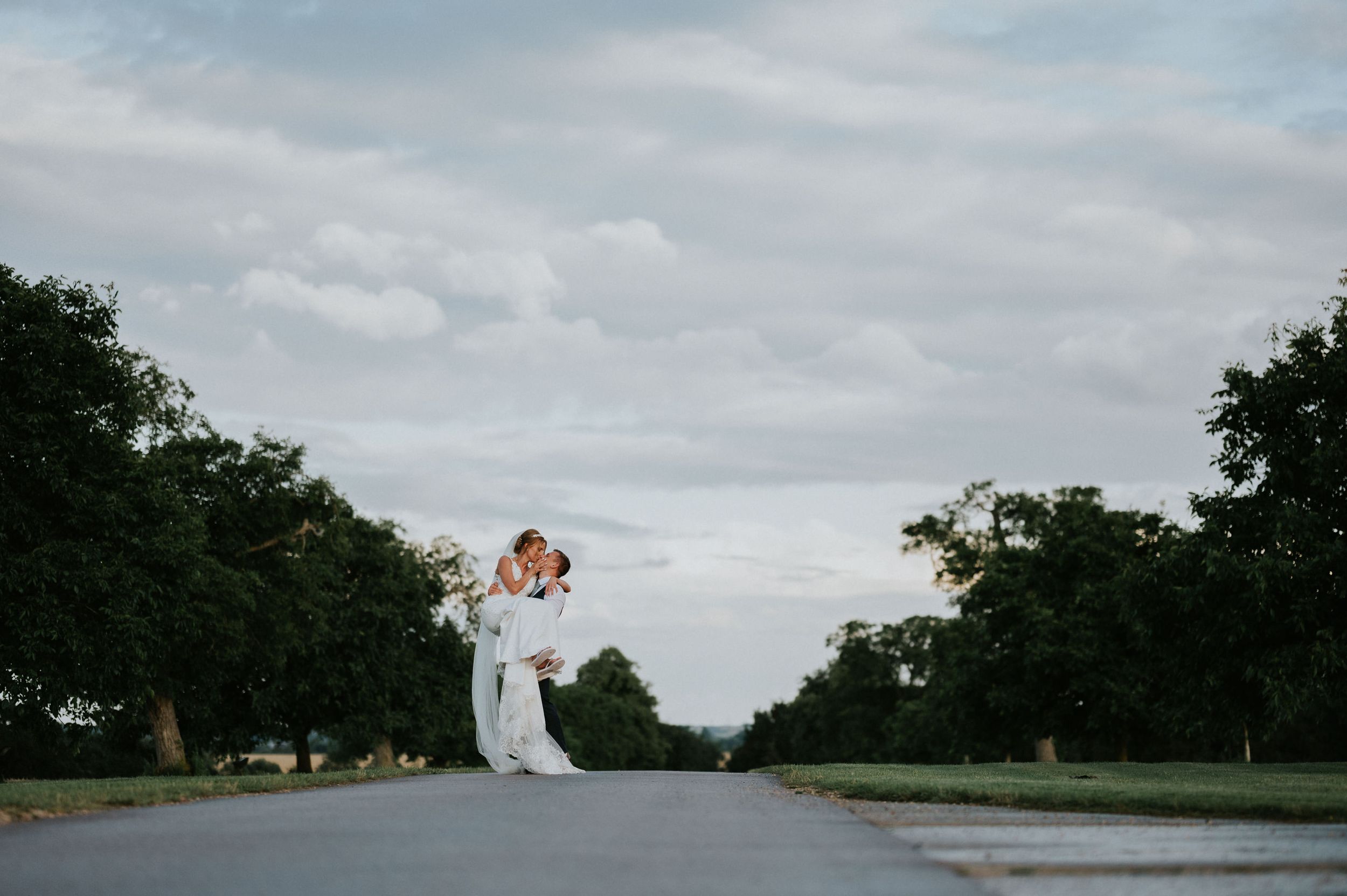 Romantic lift pose on empty road during overcast wedding photoshoot.