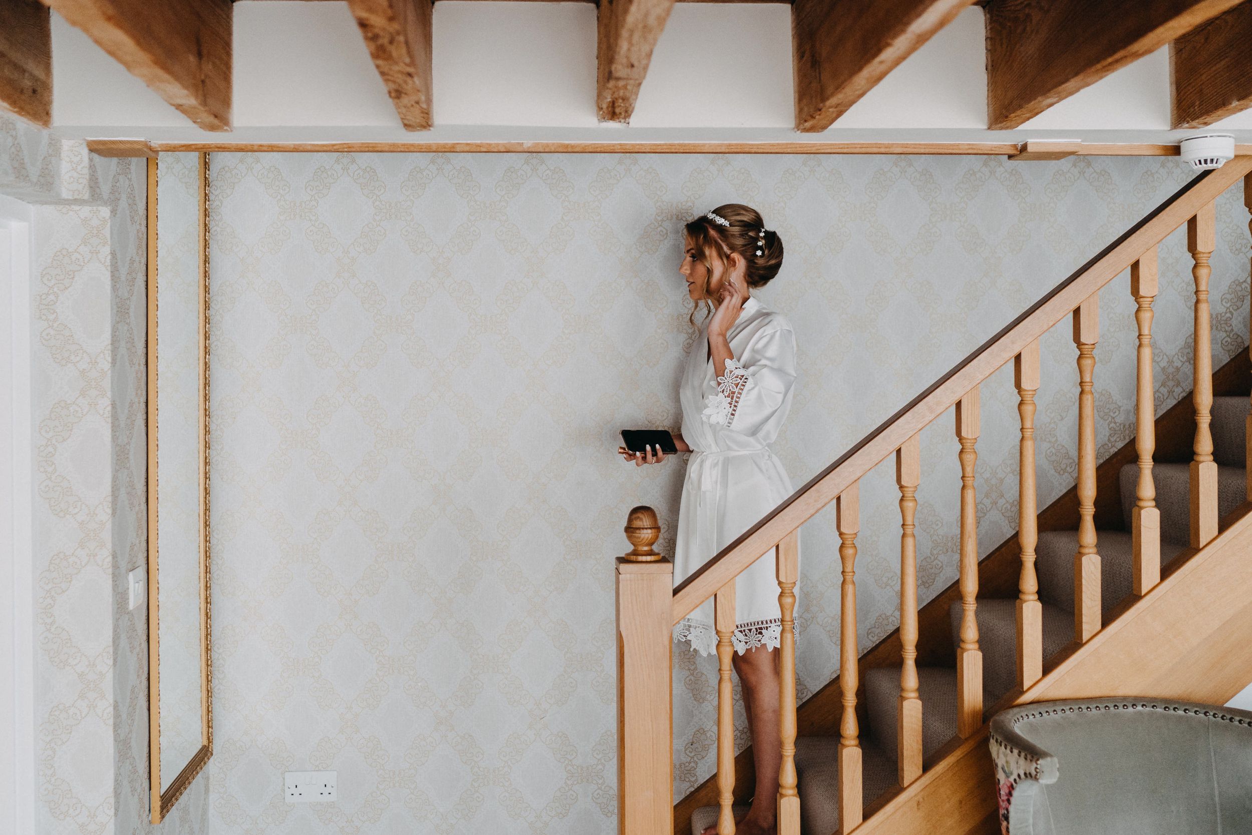 Artistic wedding photo taken on rustic staircase with white walls and wooden details.