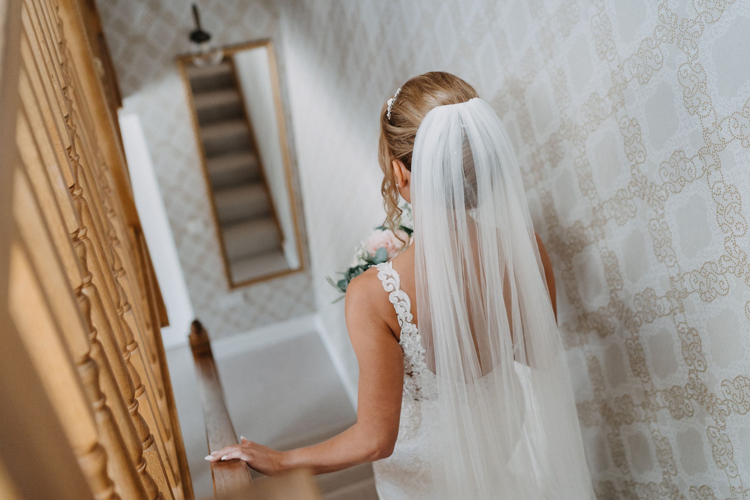 Side profile wedding photography showing intricate lace details and flowing veil.