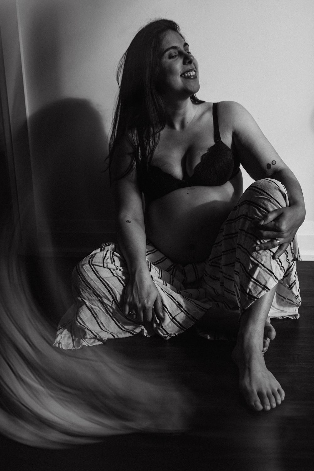 pregnant woman sitting on the floor and looking to the light getting into her apartment in York, Toronto
