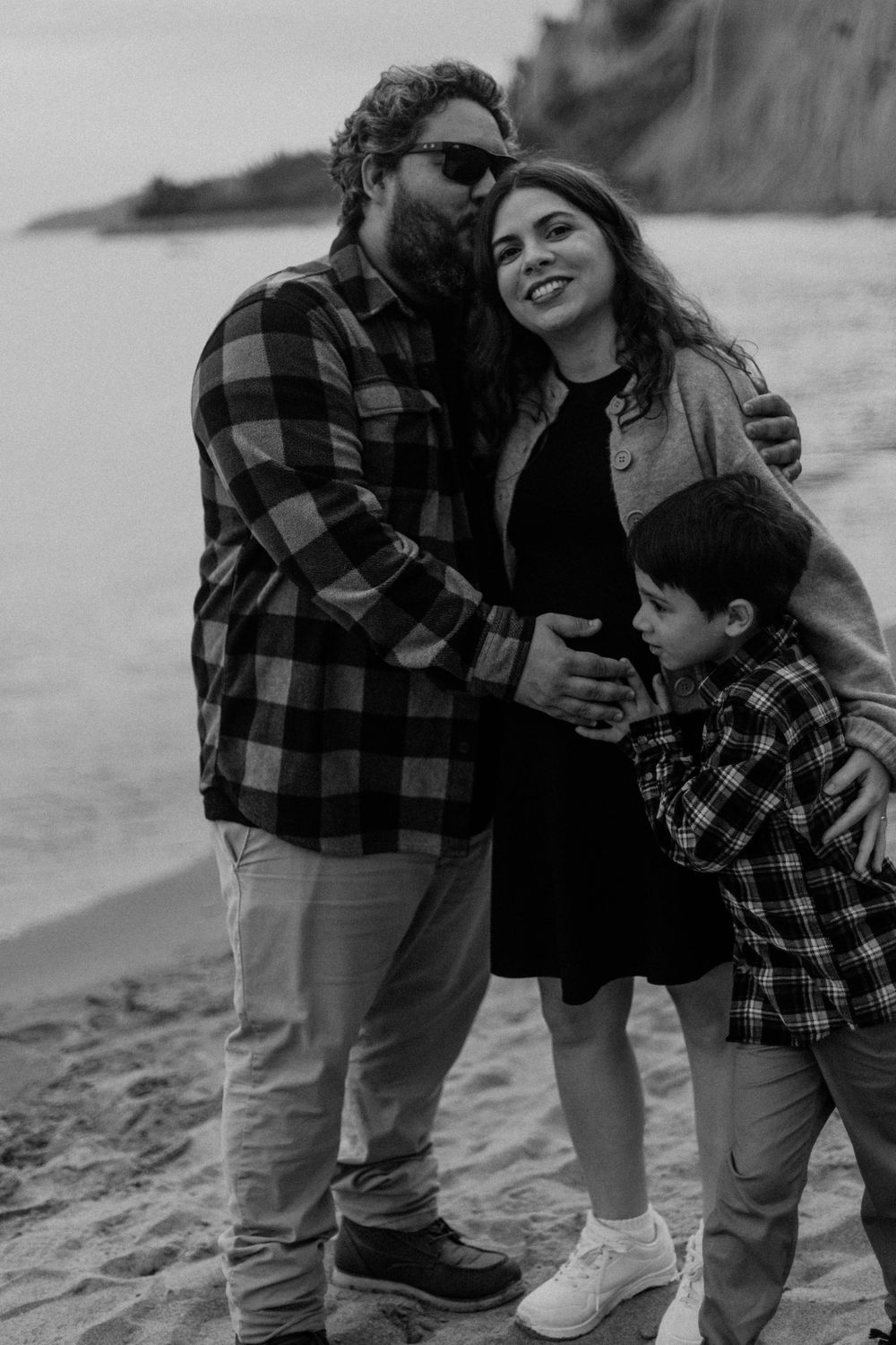 family posing on the side of the lake, expecting the new baby to come, at the Bluffs in Scarborough, Toronto