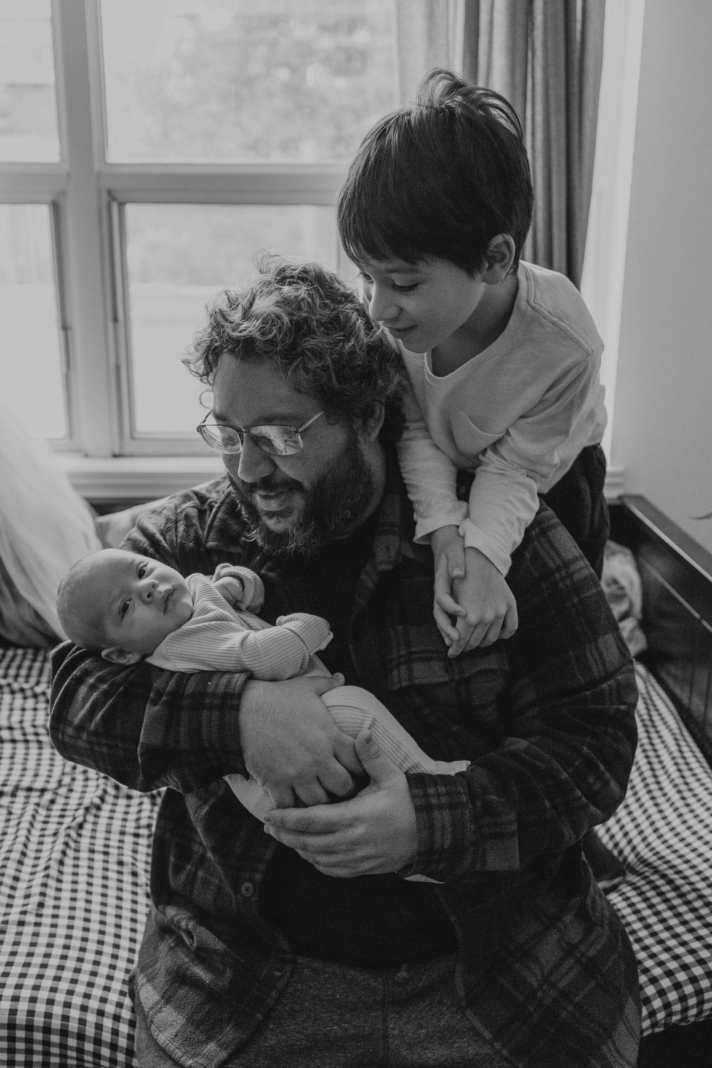 Dad and his older son looking to the newborn kid in his arms, in their living room in Etobicoke, Toronto