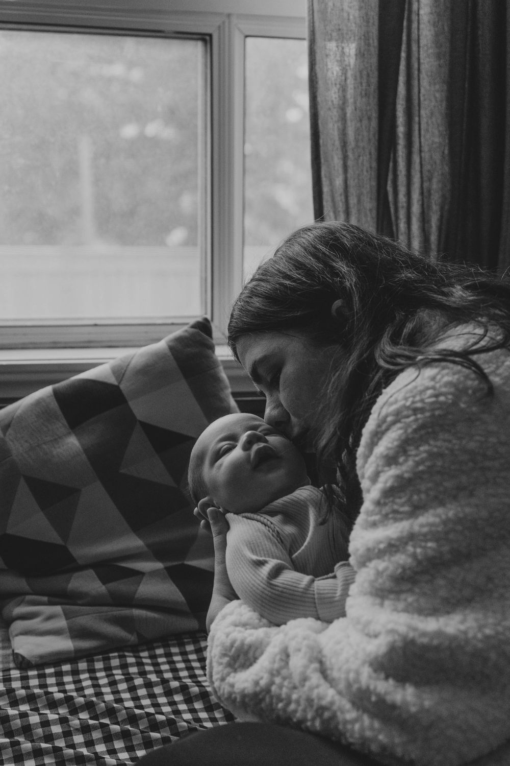 Mother kissing her newborn son in her living room in Etobicoke, Toronto.